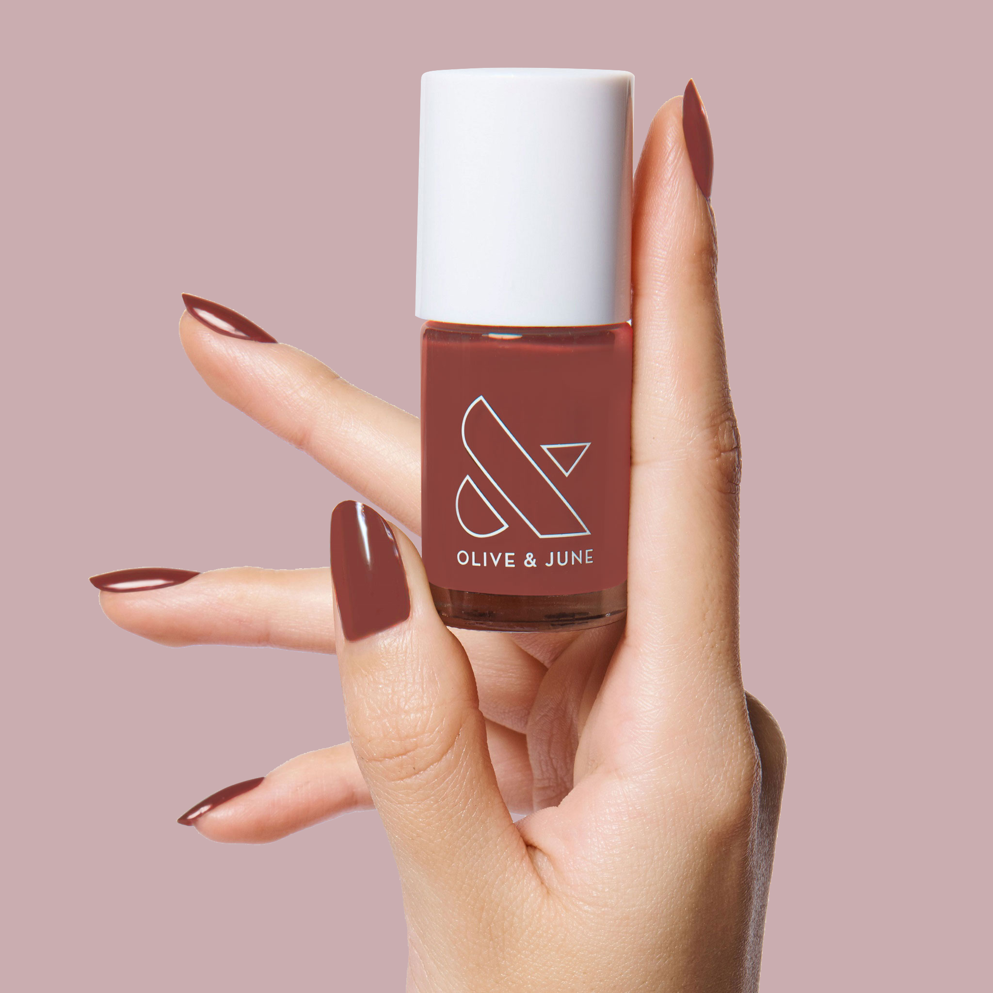 Hand holding JJ polish bottle with nails painted in warm cinnamon brown for a cozy at-home mani look