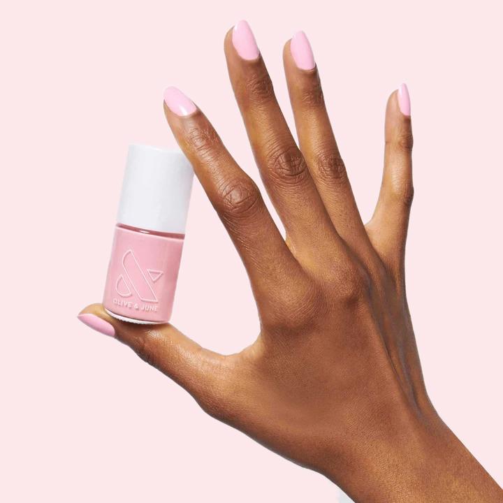 Hand holding a pink nail polish bottle with nails painted in soft pink from the Summer Sorbet Set by Olive and June