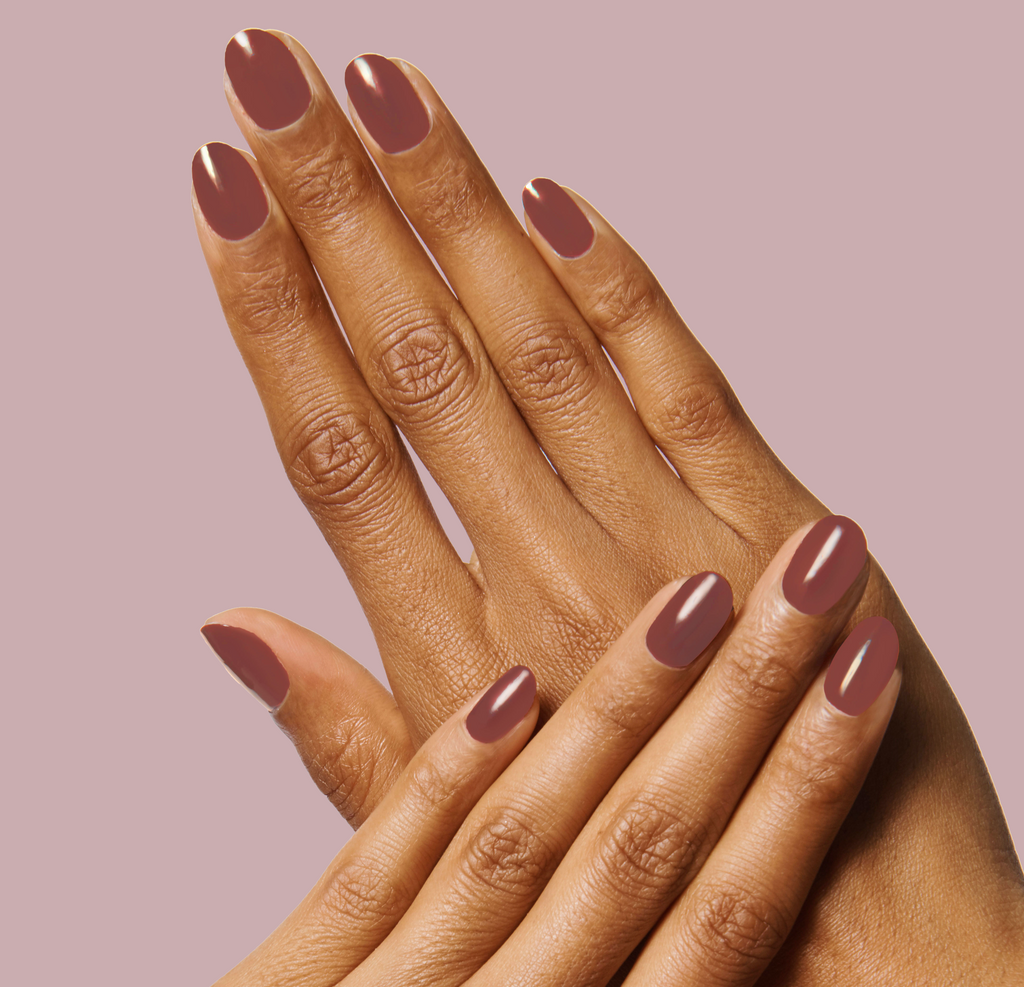 Two hands with nails painted in JJ polish, a cozy cinnamon brown shade, showcasing a neat at-home manicure.