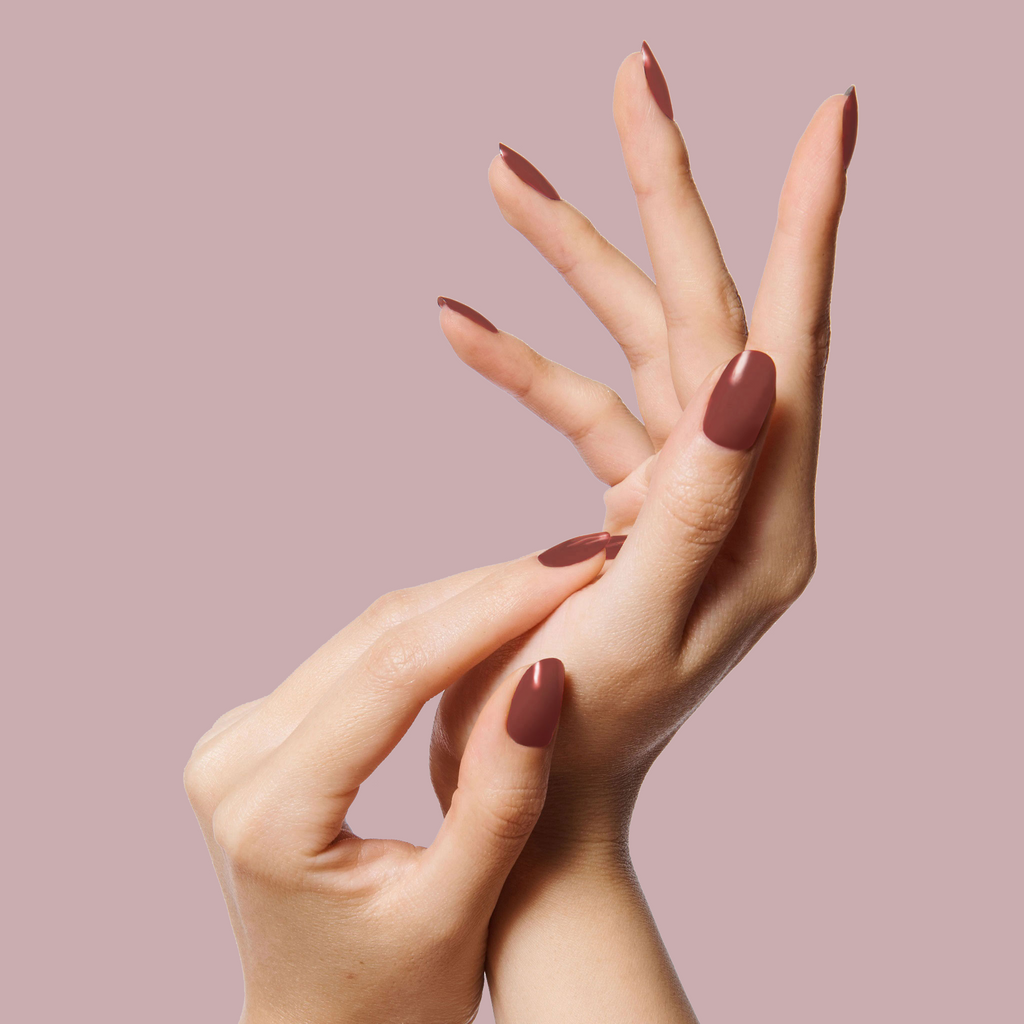 Hands with nails painted in JJ polish in a warm cinnamon brown shade showcasing a smooth at-home manicure