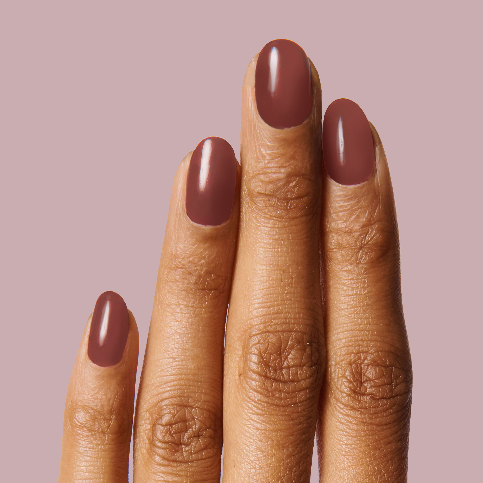 Fingers with nails painted in JJ, a cozy cinnamon brown polish, showcasing a smooth and polished manicure look