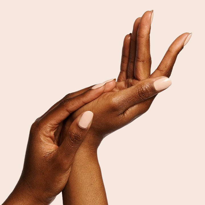 Hands with smooth neutral peachy pink KAG gel polish on nails against a soft beige backdrop for a polished manicure