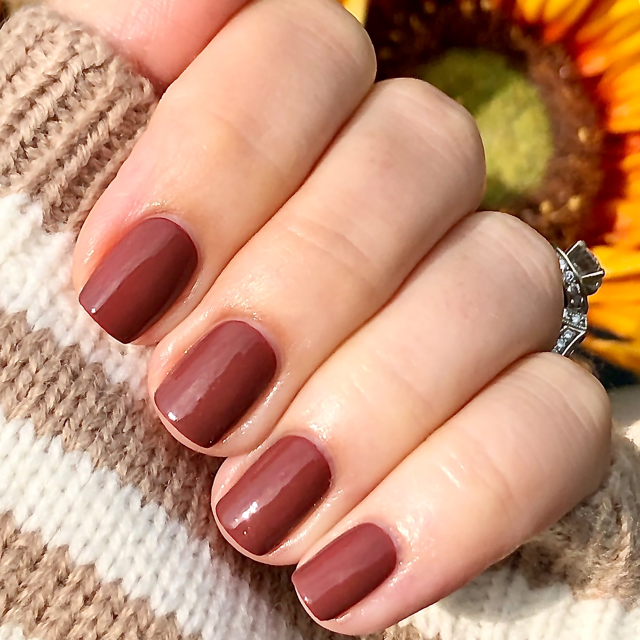 Fingers with nails painted in JJ polish, a warm cinnamon brown gel polish perfect for cozy at-home manicures