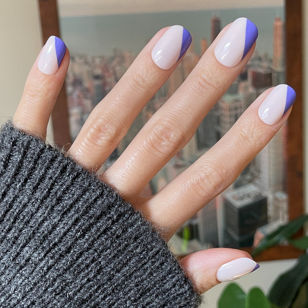 Asymmetrical French | Short | Squoval - Tab Press-On nails with indigo angled tips on neutral base worn with gray sweater
