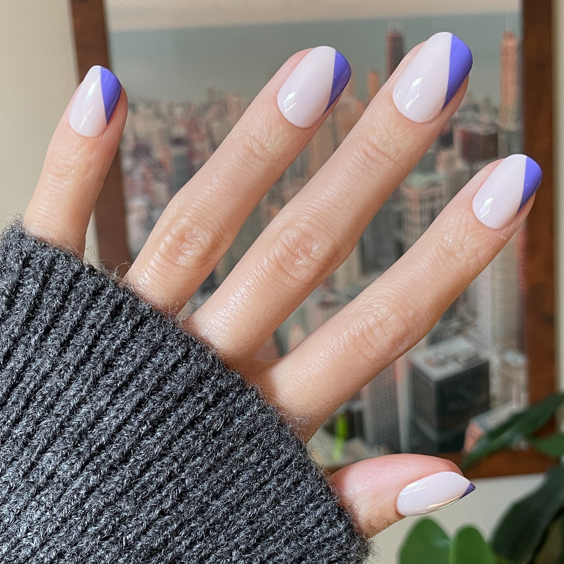 Asymmetrical French | Short | Squoval - Tab Press-On nails with indigo angled tips on neutral base worn with gray sweater