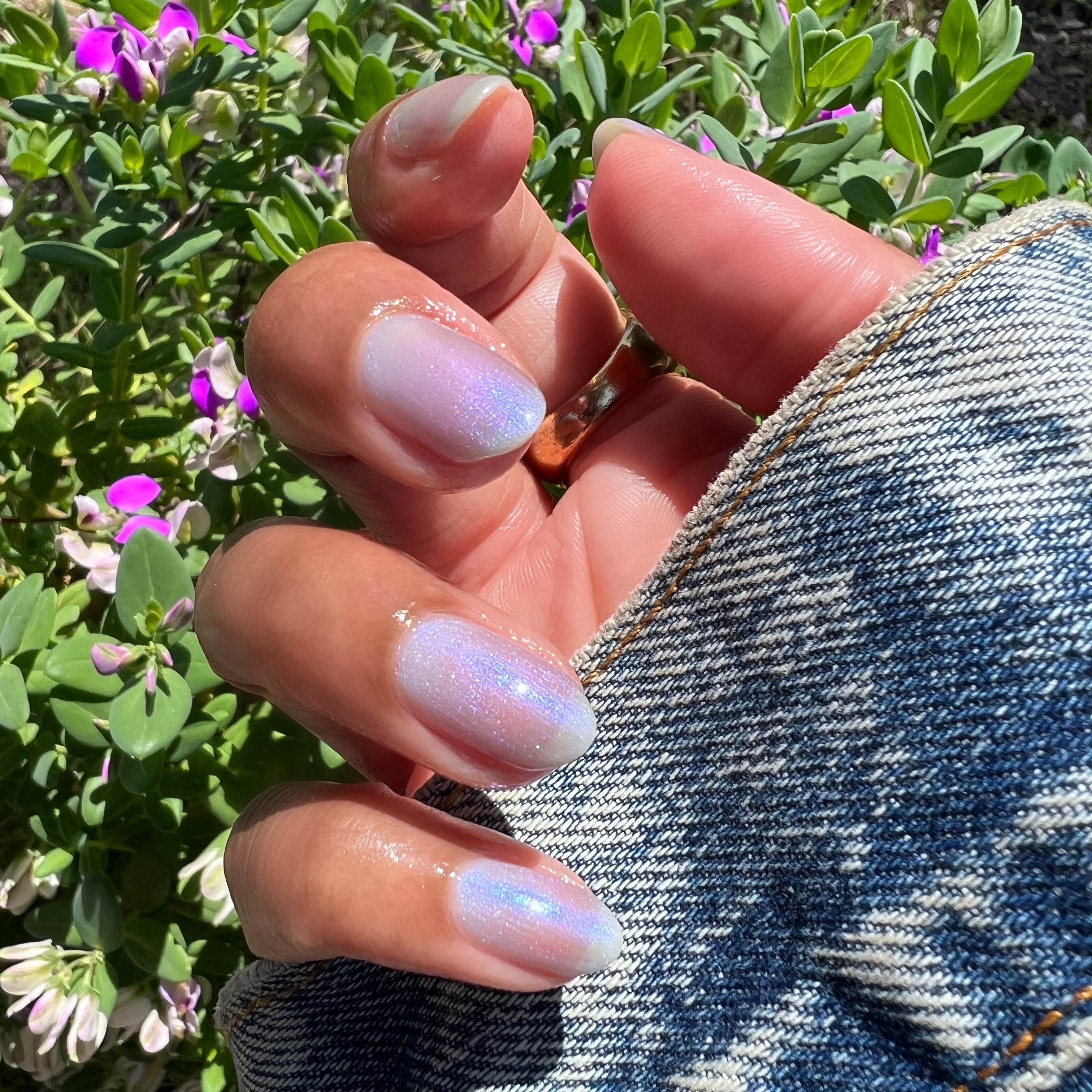 Hand with nails painted in sheer lavender-blue iridescent manicure using Friend or Anemone? polish outdoors