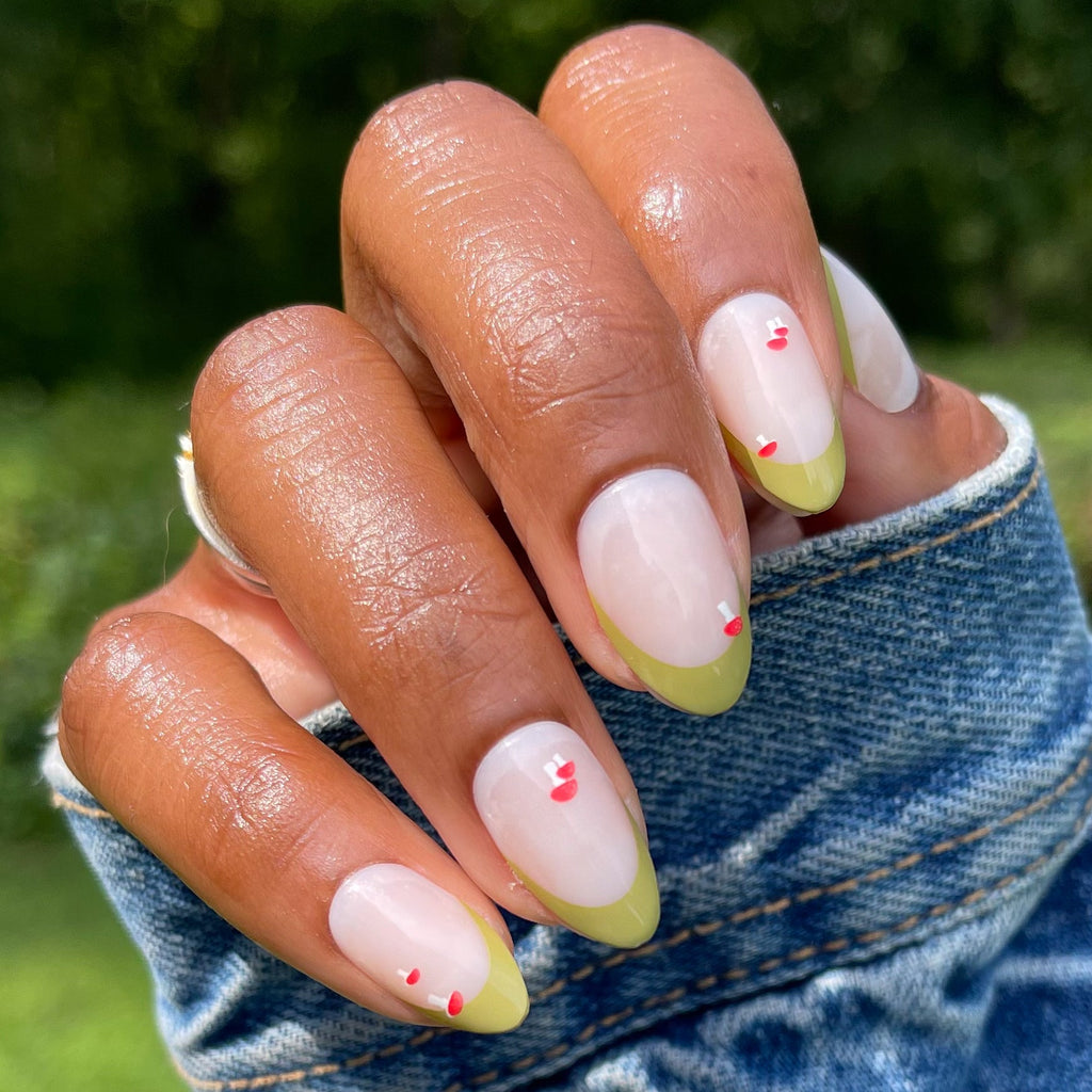 Mushroom Fall French - Press-On | Medium | Almond nails with green french tips and small red mushroom details on hand outdoors
