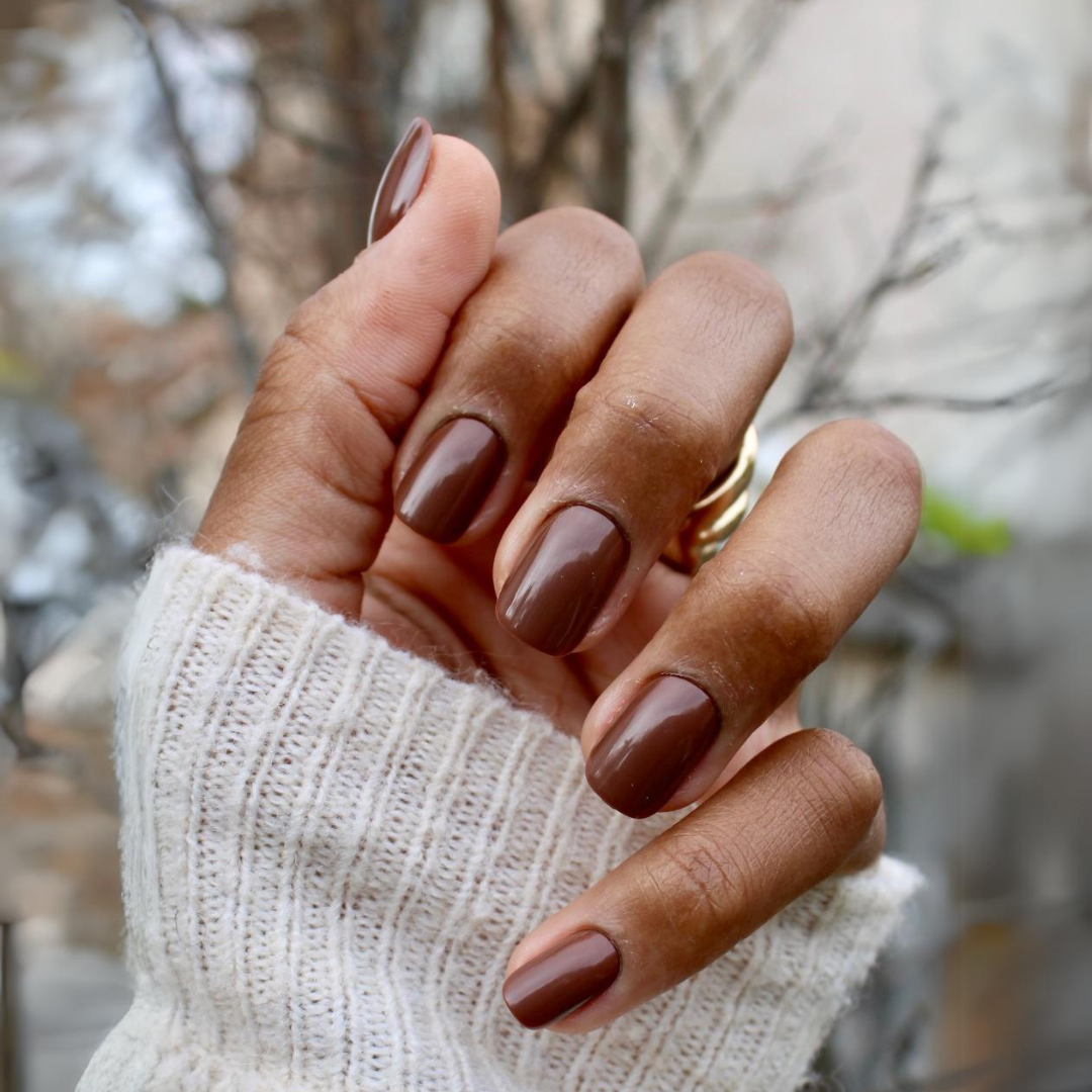 Americano | Short | Squoval - Tab Press-On showing hand with glossy coffee brown short false nails outdoors in cozy sweater