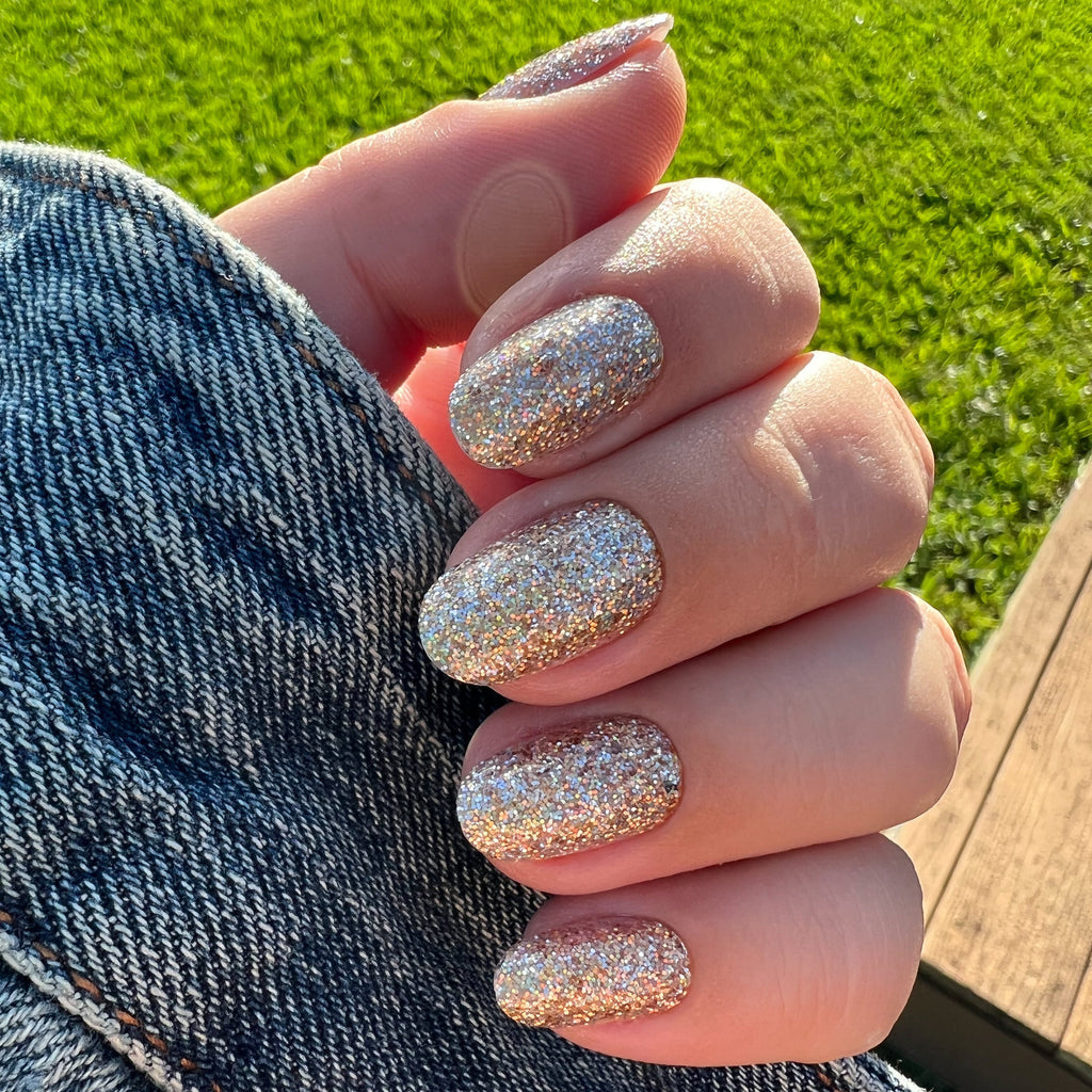 OBVI - Press-On | Medium | Oval hand displaying medium oval false nails in sparkling gold glitter for a festive mani look