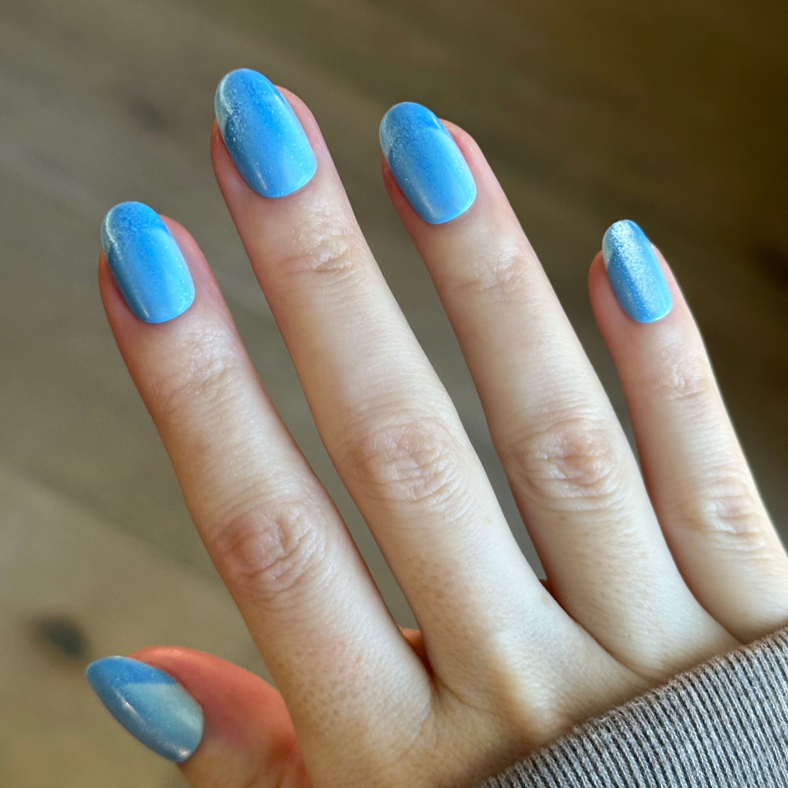 Axolotl Velvet Illusion French - Press-On | Short | Round showing hand with shimmering blue velvet press-on false nails and subtle French tips