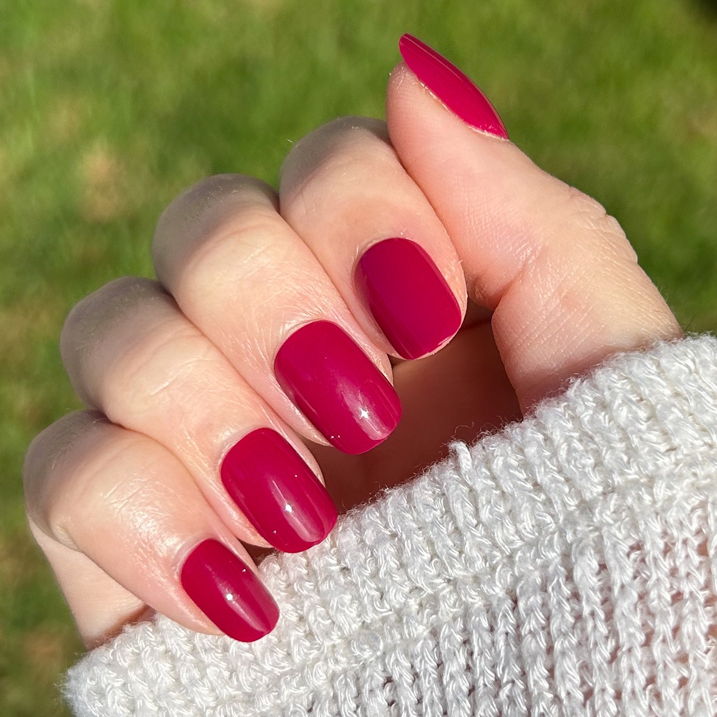 Mulberry | Extra Short | Squoval - Tab Press-On showing deep maroon press-on nails on hand with cozy white sweater outdoors