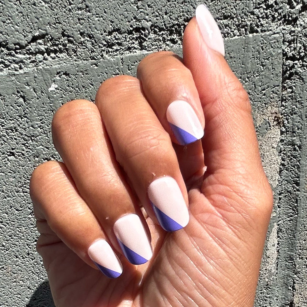 Asymmetrical French | Short | Squoval - Tab Press-On nails with indigo diagonal tips on natural base on hand outdoors