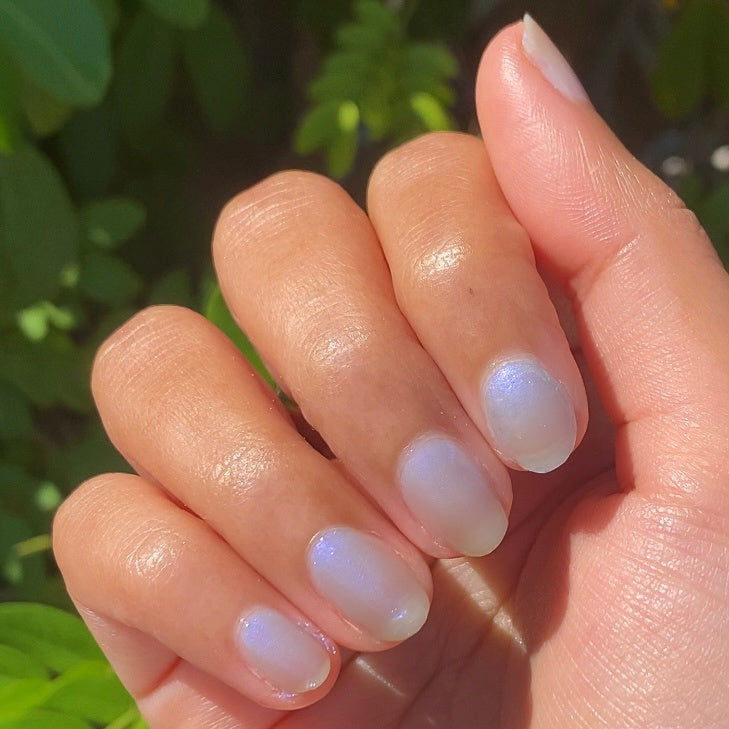 Hand showing nails painted in sheer lavender-blue iridescent manicure with Friend or Anemone? polish in natural light outdoors