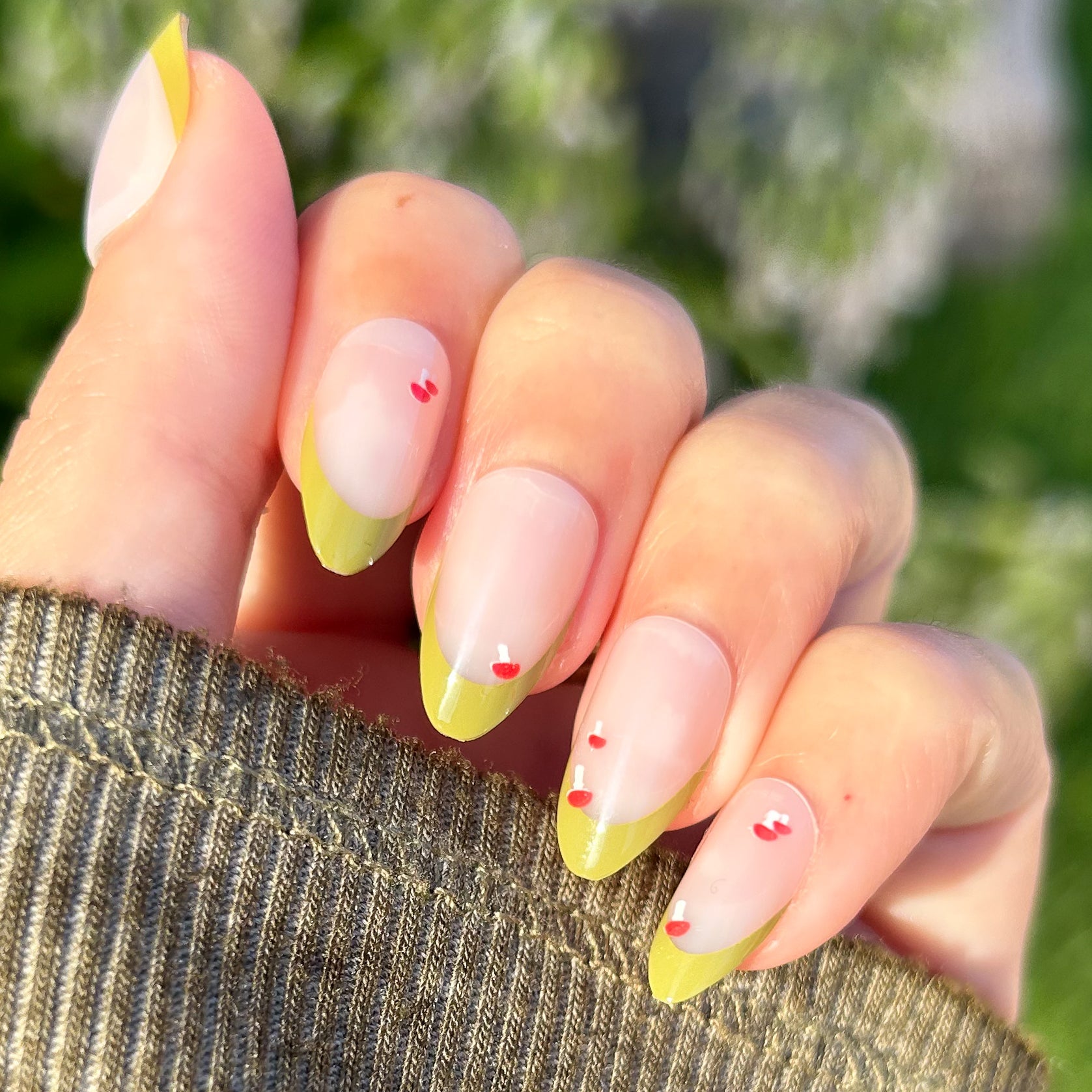 Mushroom Fall French - Press-On | Medium | Almond nails with muted green tips and tiny red mushroom details on hand outdoors