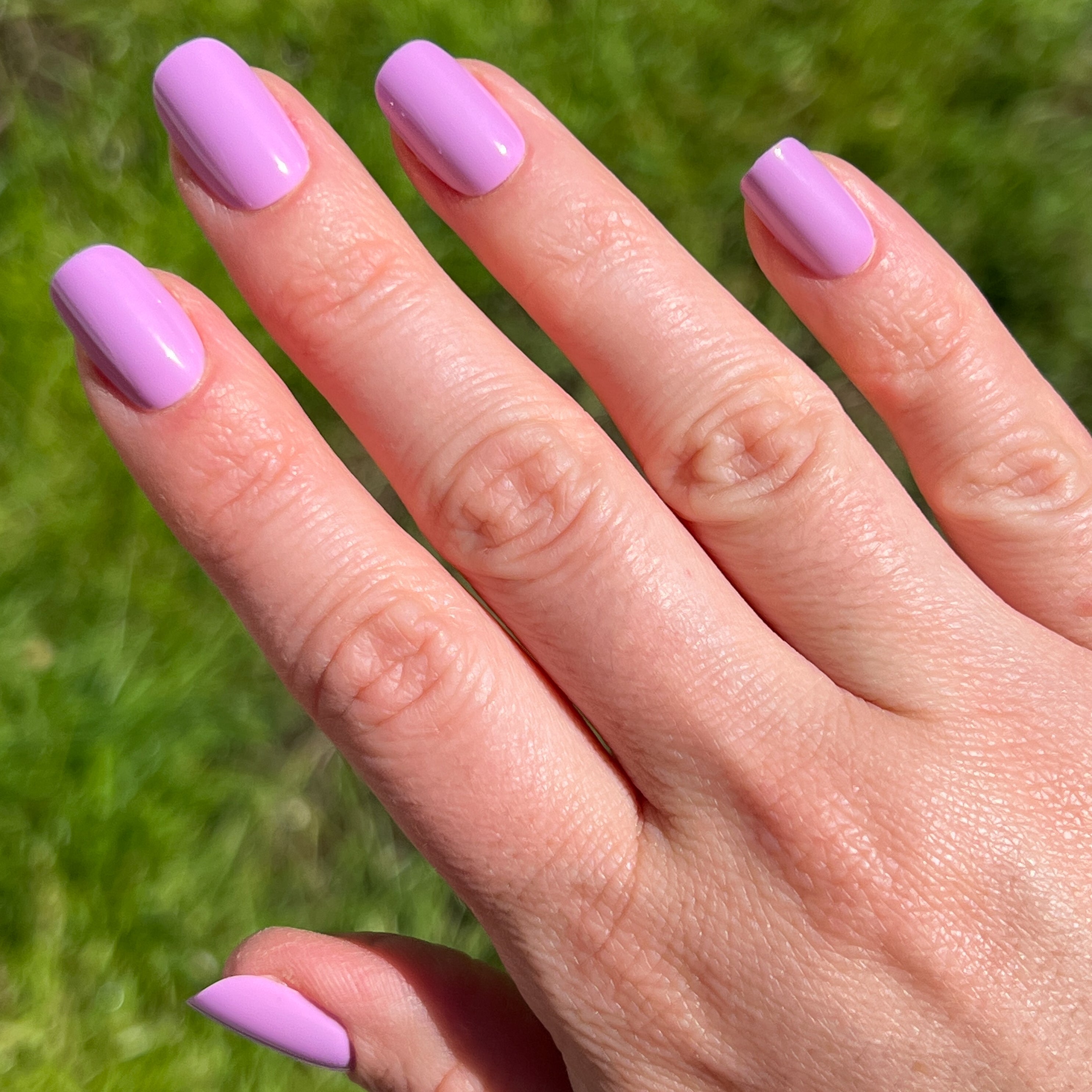 Hand with Fierce & Loving | Squoval | Short lilac short squoval press-on nails in natural light on grass background