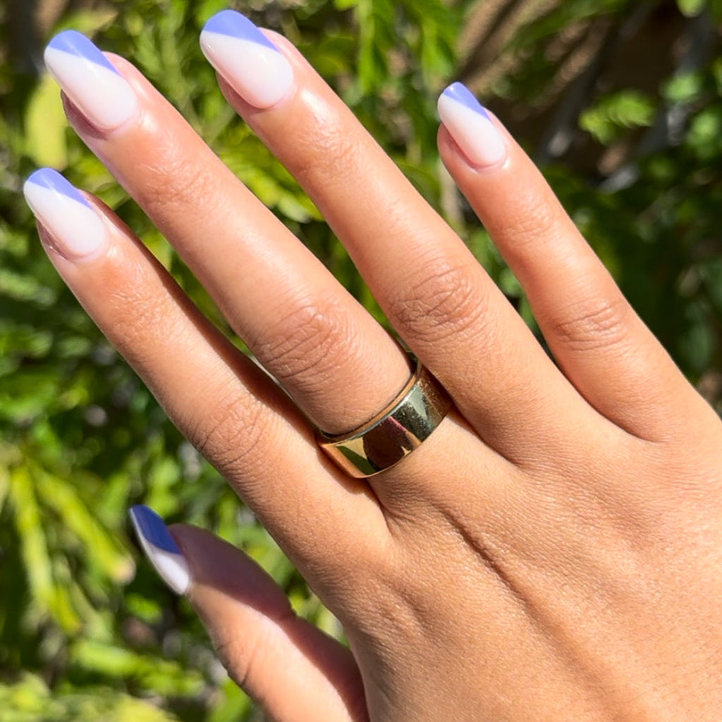 Asymmetrical French | Short | Squoval - Tab Press-On nails with indigo tipped diagonal design on natural base on hand outdoors