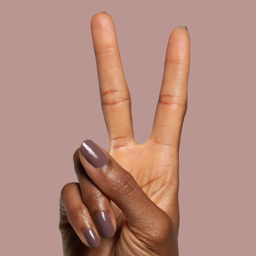 Hand with glossy Clocking Out Early gel polish manicure in a neutral minky brown on a soft mauve background