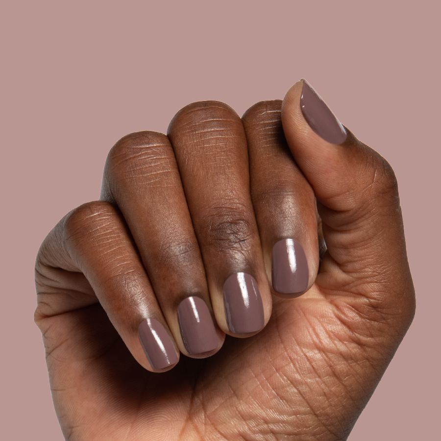 Hand with Clocking Out Early gel polish manicure in a smooth neutral minky brown on a soft mauve background