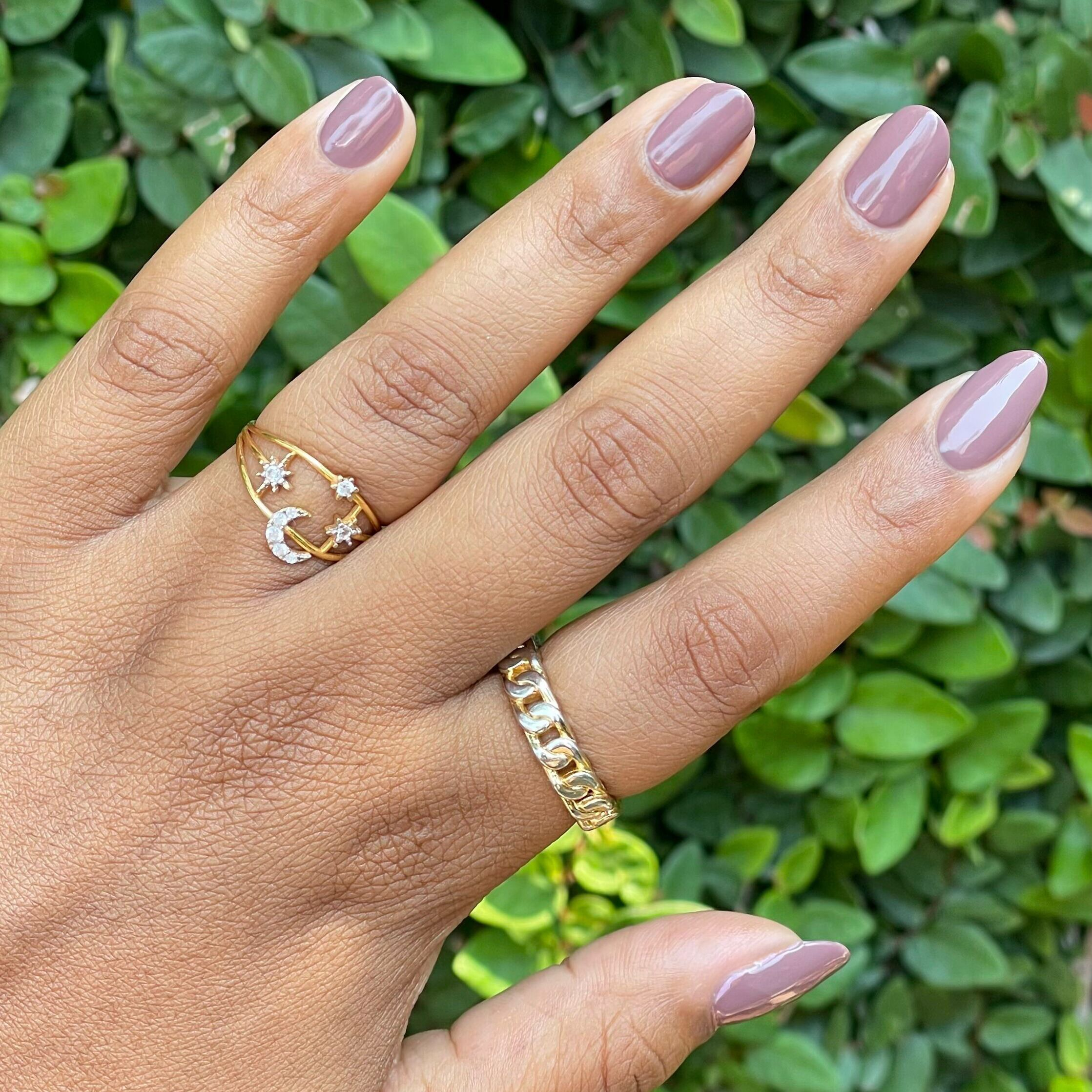 Hand with glossy Clocking Out Early neutral minky brown gel polish manicure against green leafy background