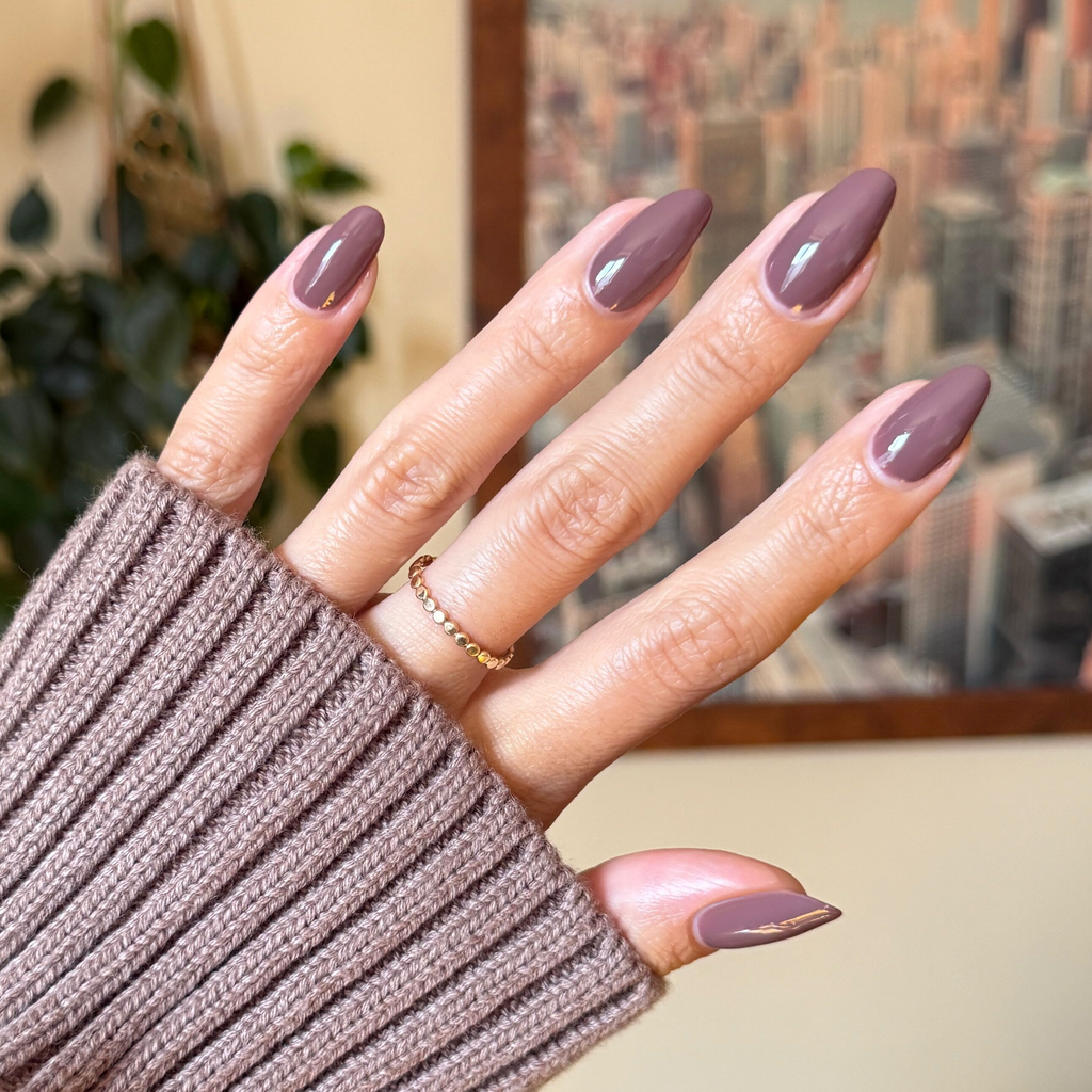 Hand with glossy Clocking Out Early gel polish manicure in a soft neutral brown shade on a cozy knit background