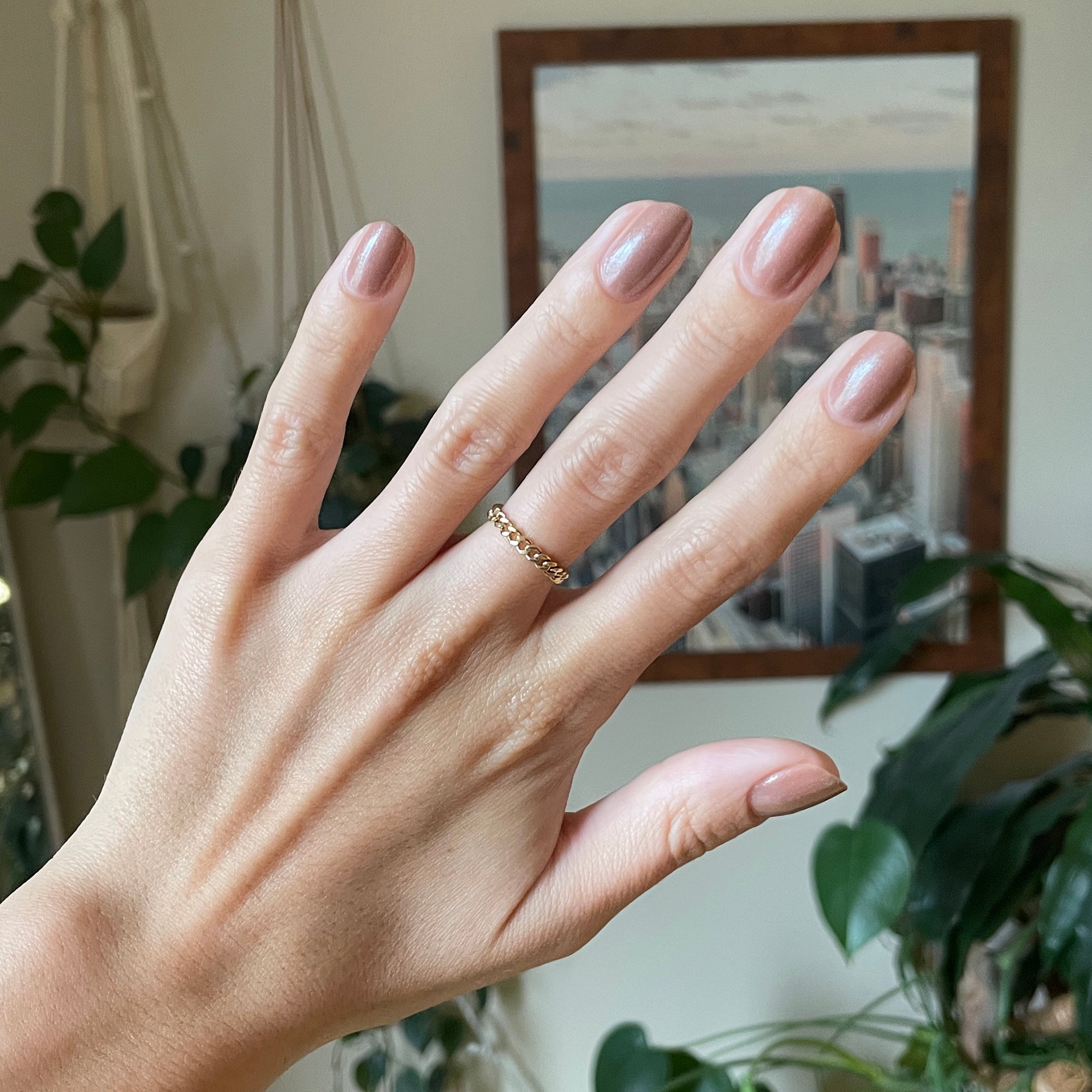 Hand with nails polished in sheer warm chestnut Coconut Shimmer Gloss gel polish with subtle silver sparkle