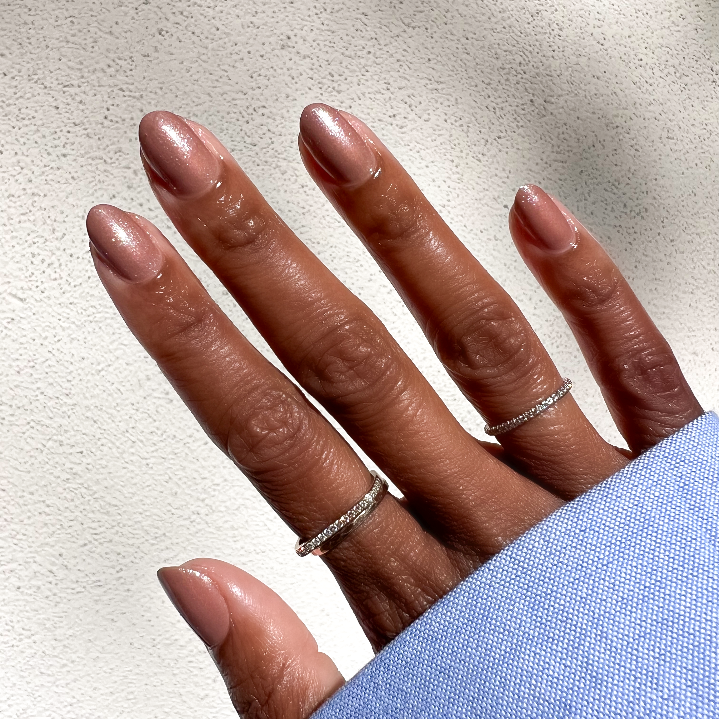 Hand with almond-shaped nails featuring sheer warm chestnut Coconut Shimmer Gloss gel polish with silver sparkle```