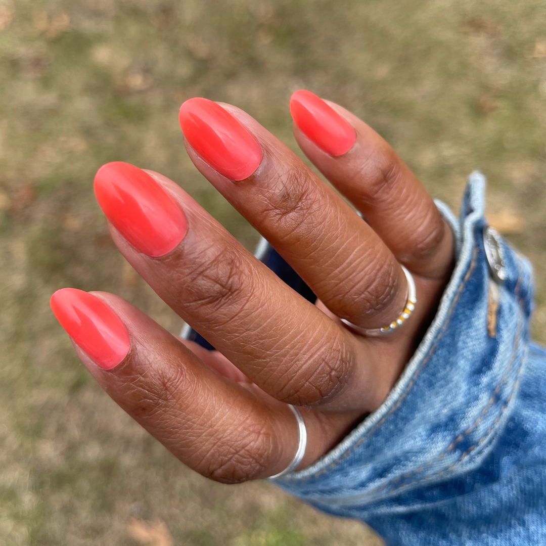 Coral Jelly - Press-On | Medium | Oval showing medium oval semi-sheer coral press-on nails on hand with silver rings outdoors