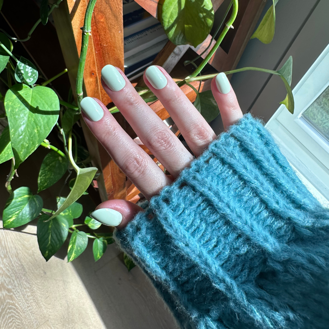 Corrigan | Extra Short | Round - Tab Press-On nails in pastel mint green on natural nails with cozy blue sweater background