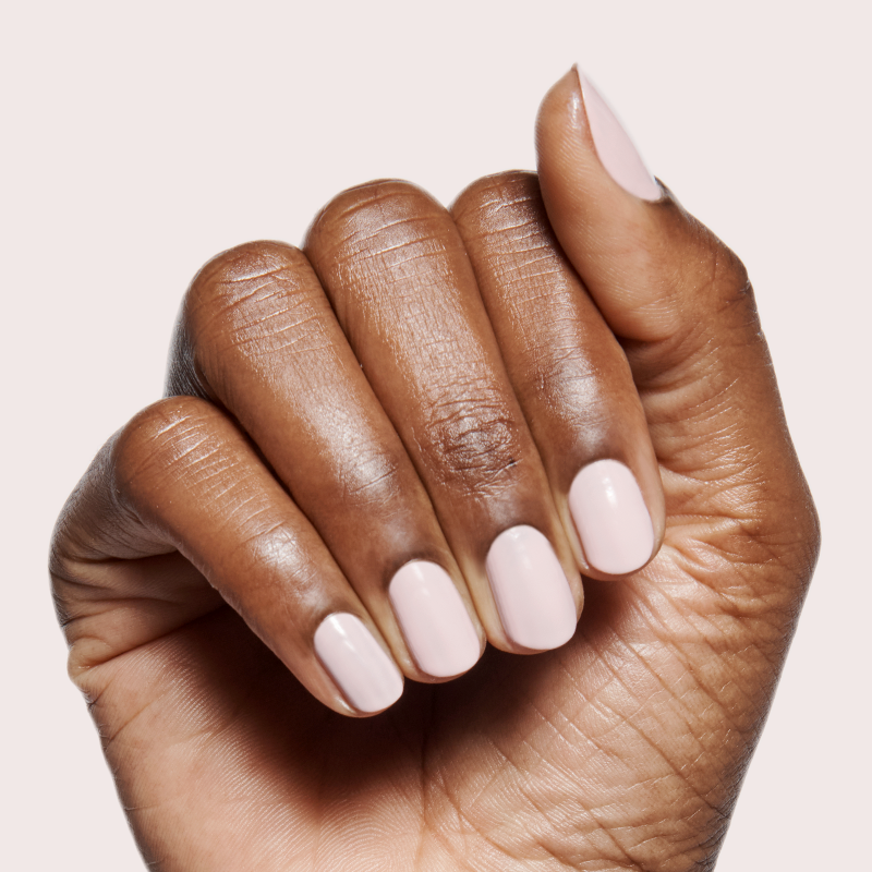 Hand with milky sheer pink manicure using Dream Job long-lasting polish against pale neutral background