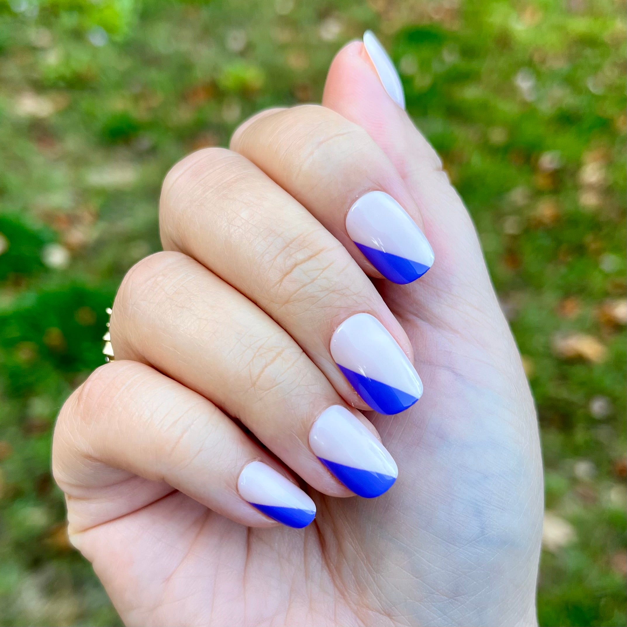 Asymmetrical French | Short | Squoval - Tab Press-On nails with indigo diagonal tips on natural base outdoors