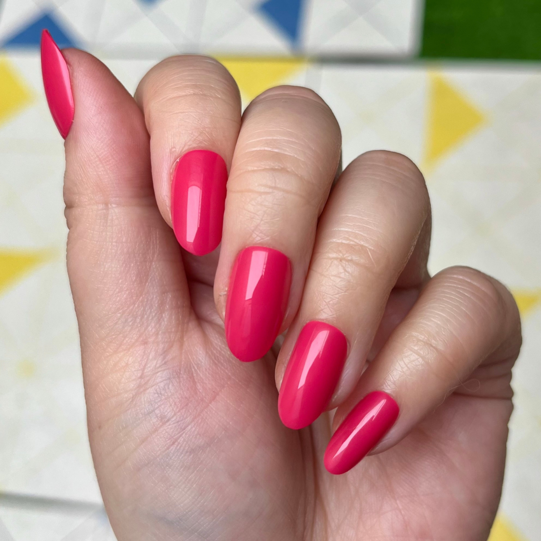 Diner Date - Press-On | Medium | Oval showing hand with medium oval hot pink press-on nails against colorful patterned background
