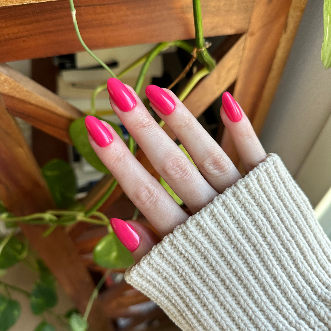 Diner Date - Press-On | Medium | Oval showing hand with bright hot pink medium oval press-on nails indoors near plants