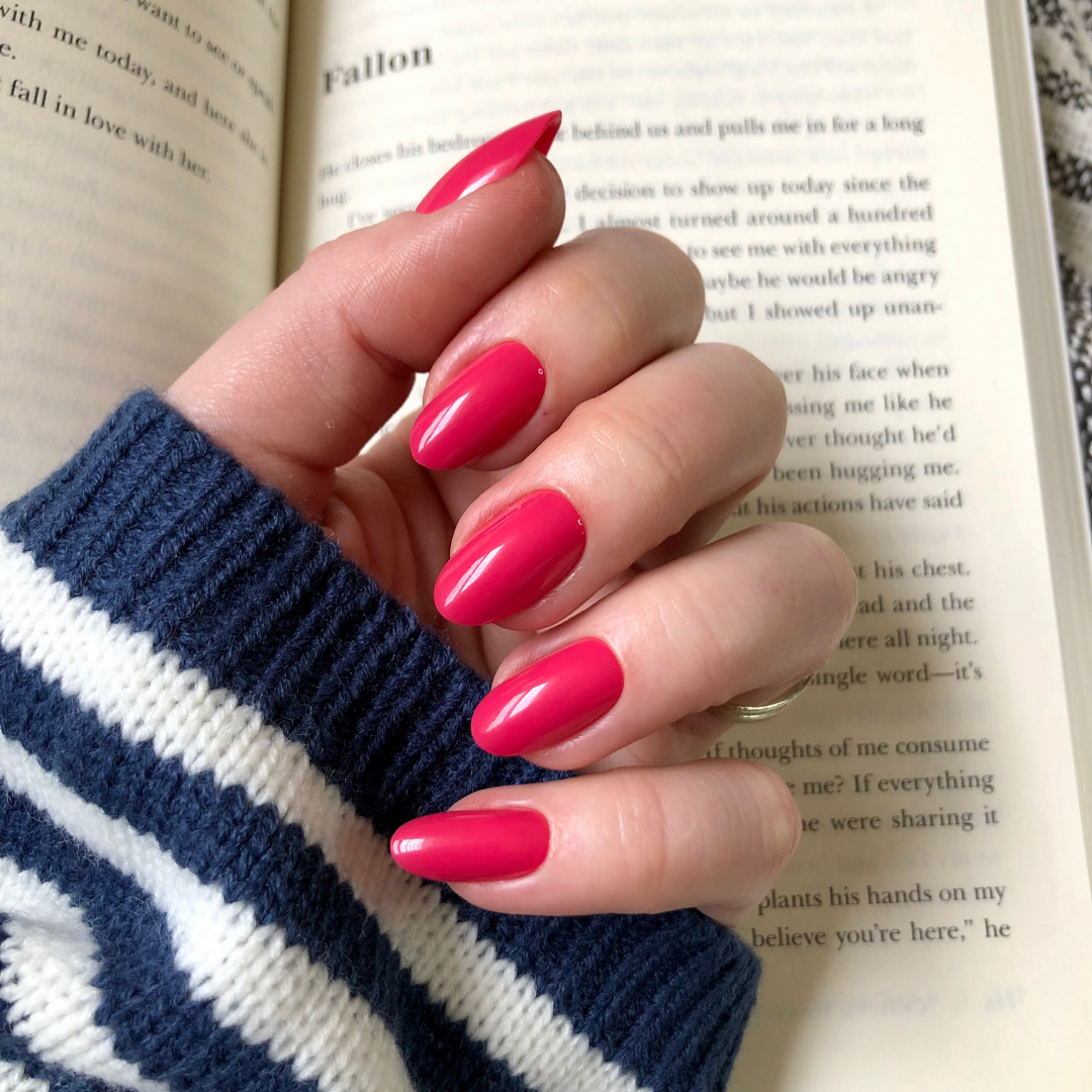 Diner Date - Press-On | Medium | Oval showing hand with medium oval bright pink press-on nails over open book text