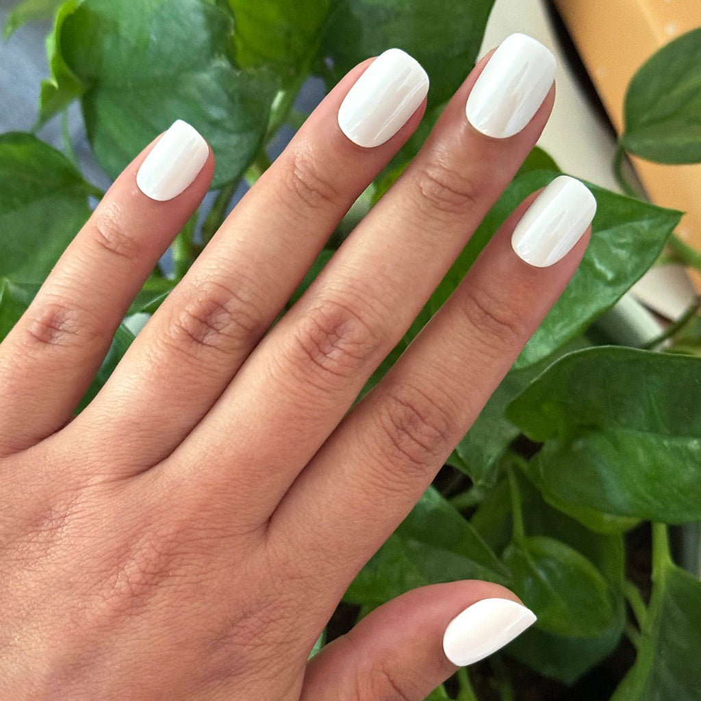 White Chrome - Press-On | Extra Short | Squoval off-white chrome press-on nails on hand with green leaves background