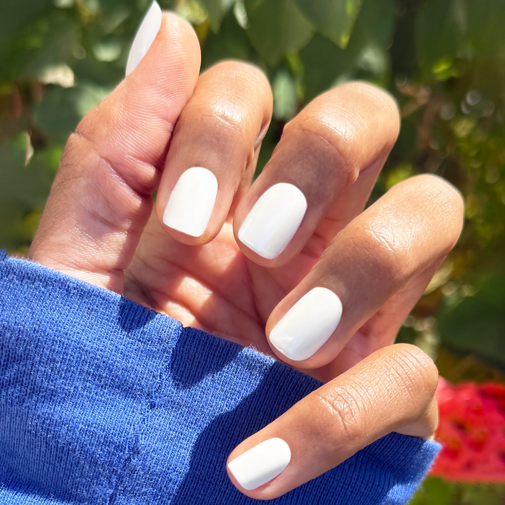 White Chrome - Press-On | Extra Short | Squoval off-white shiny press-on nails on hand outdoors with green foliage background
