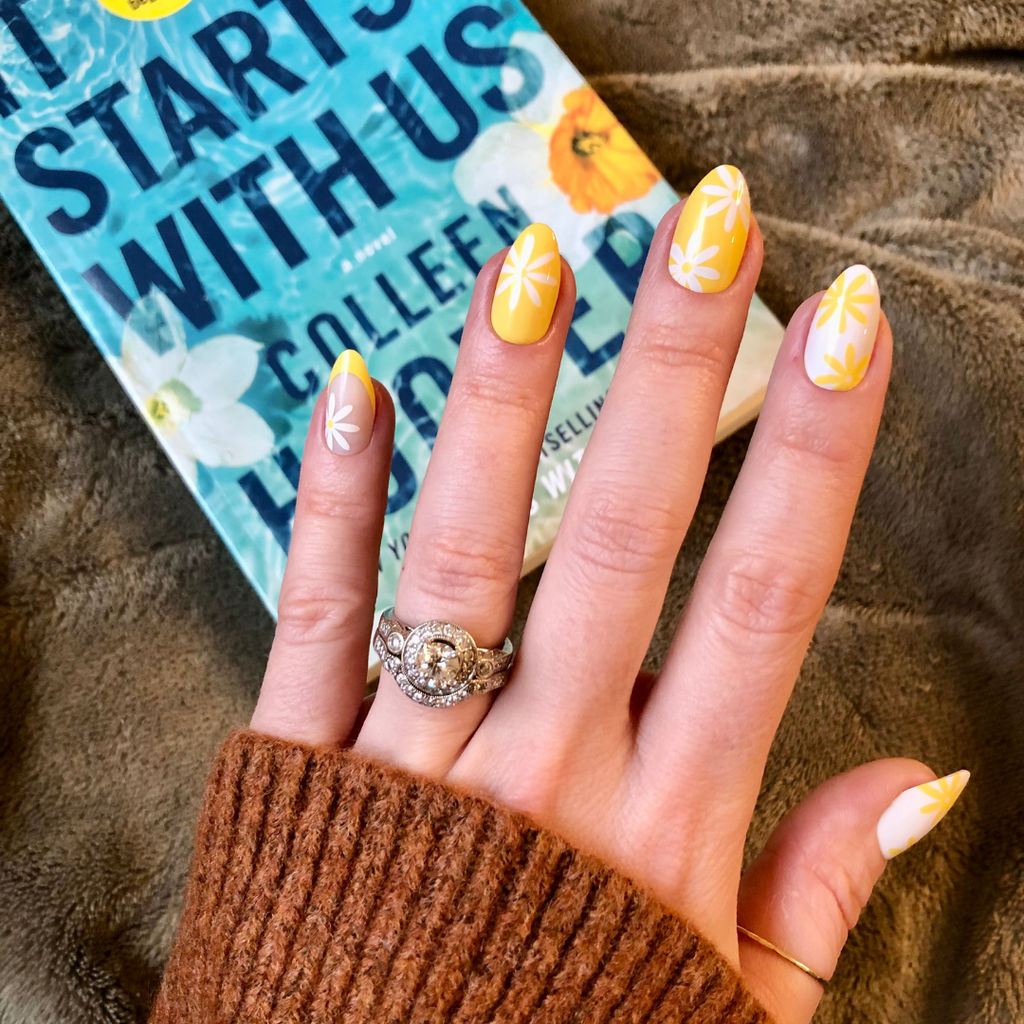 Floral Fun - Press-On | Medium | Almond showing hand with yellow and white floral false nails holding book titled Start With Us