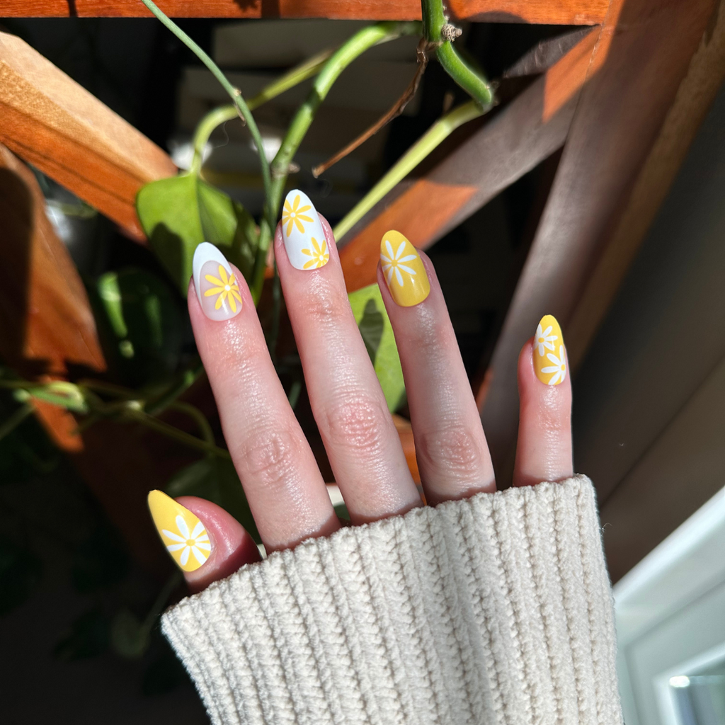 Floral Fun - Press-On | Medium | Almond showing hand with marigold and white floral french manicure press-on nails in sunlight