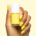 Hand holding bottle and showing nails painted in bright electric yellow Game Set Mani polish for a long-lasting mani