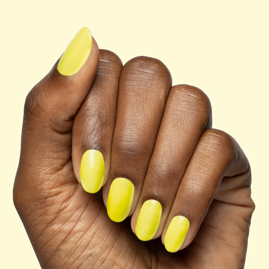 Hand with nails painted bright electric yellow Game Set Mani polish for a vibrant and quick-dry mani look