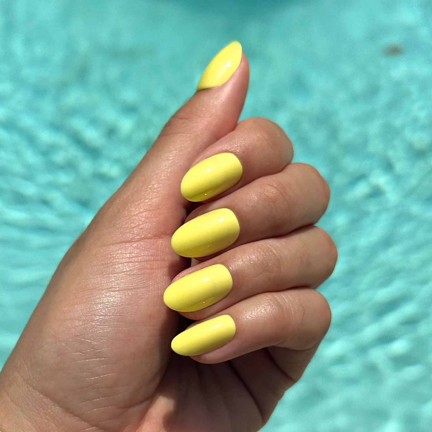Hand with nails in bright neon yellow using Game Set Mani - Press-On | Medium | Oval for a vibrant at-home mani