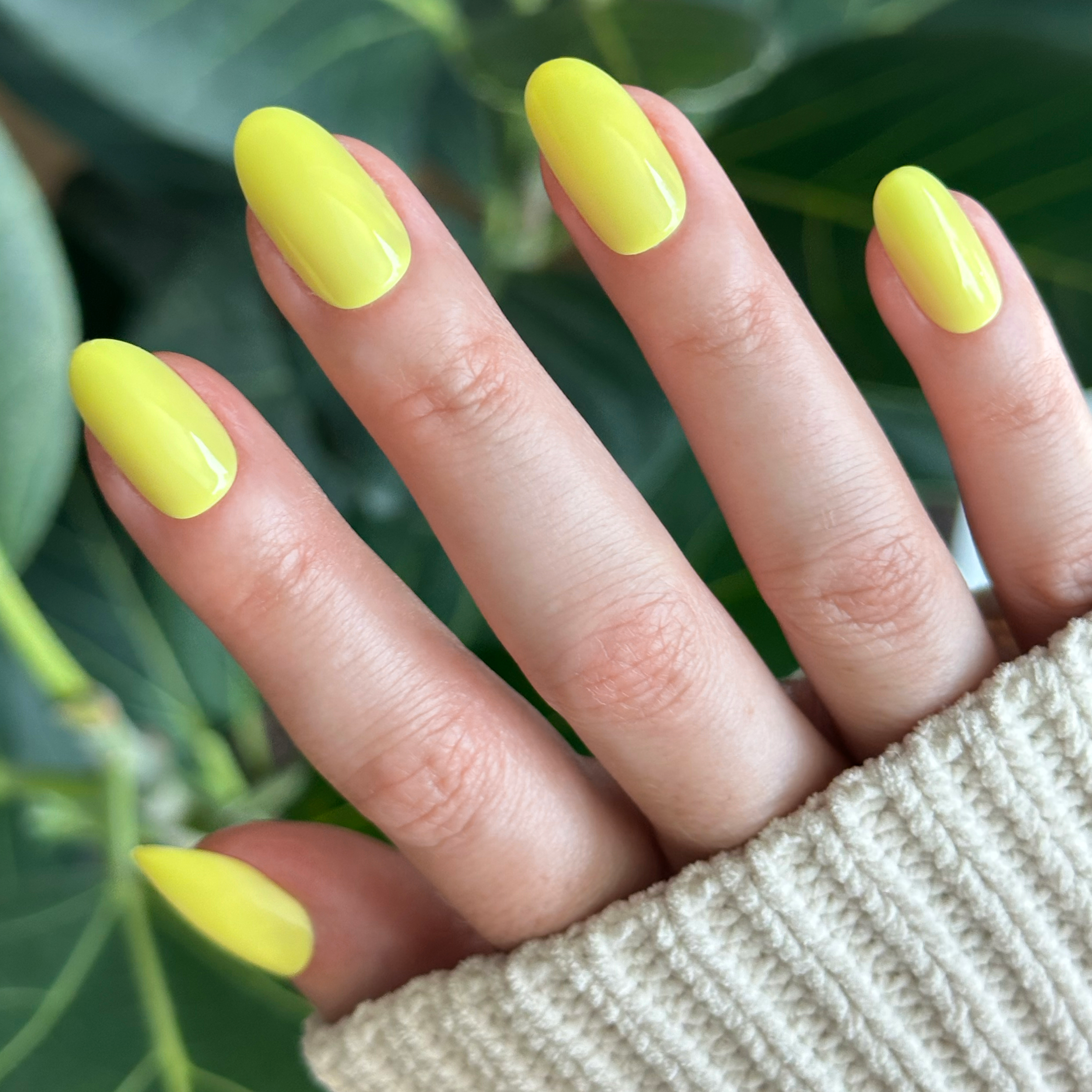 Hand with nails in bright yellow using Game Set Mani - Press-On | Medium | Oval for a sunny at-home manicure look