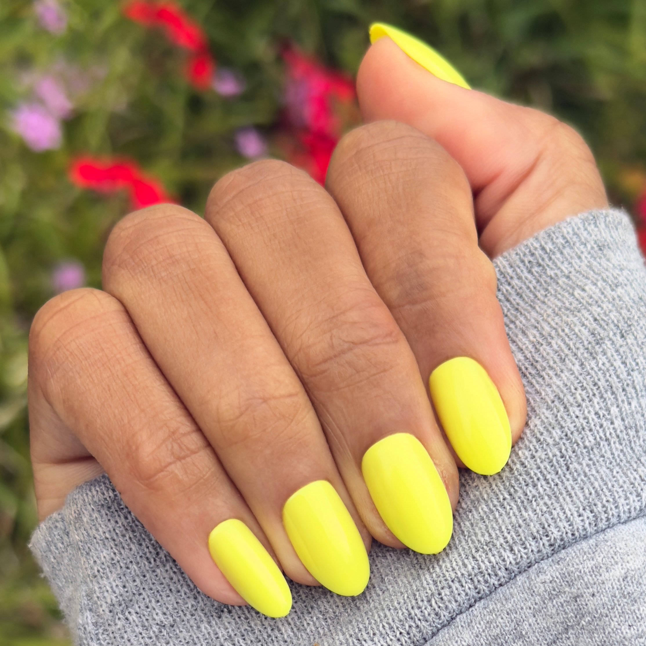 Hand with nails in neon yellow shade wearing Game Set Mani - Press-On | Medium | Oval for a bright, at-home manicure look