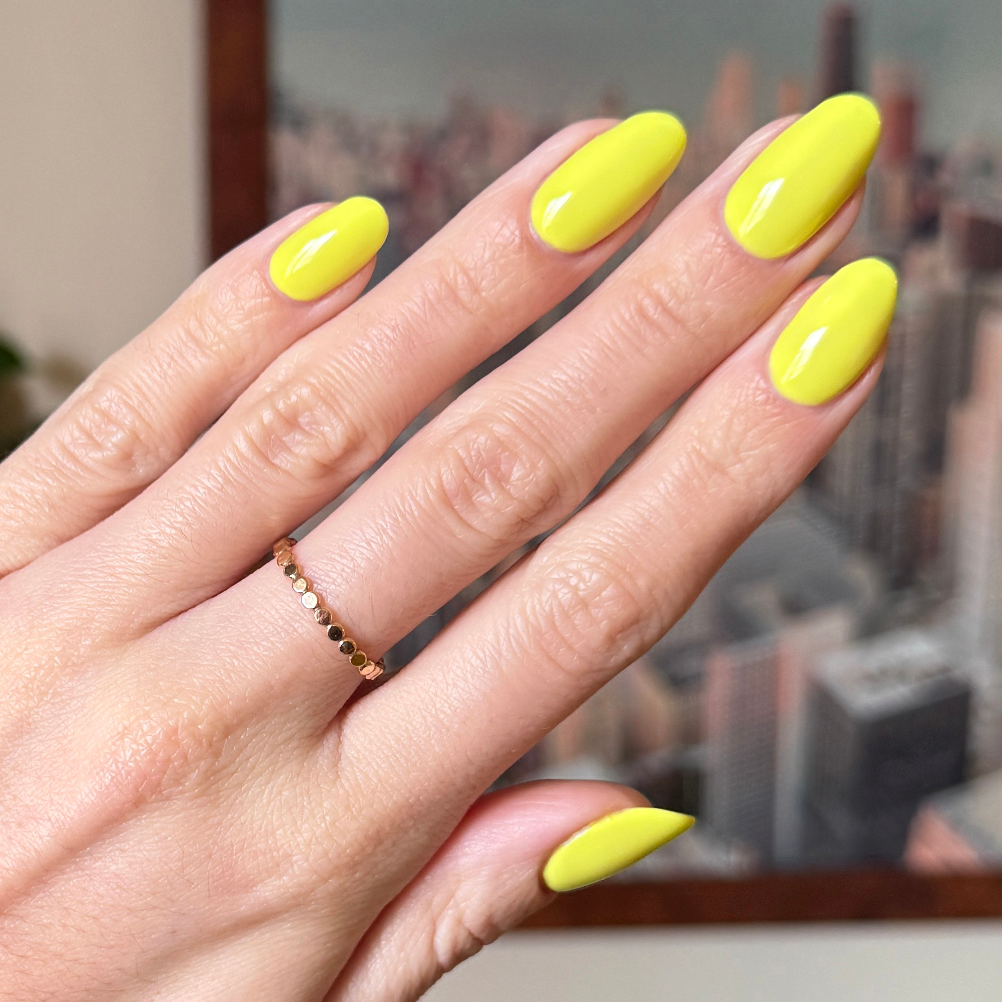 Hand with nails painted bright electric yellow Game Set Mani polish for a glossy quick-dry manicure look