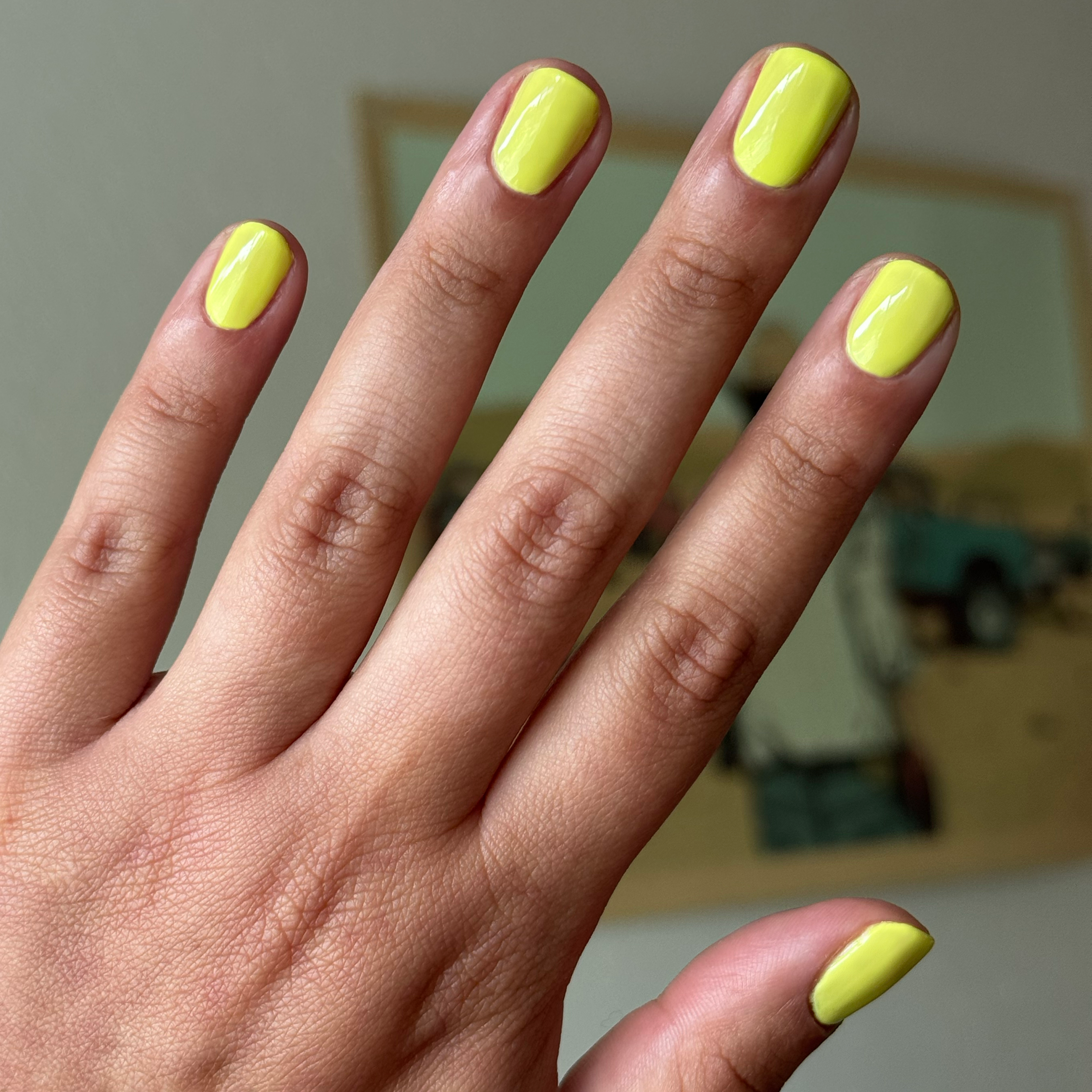 Hand with nails painted bright electric yellow Game Set Mani polish for a glossy quick-dry manicure look at home