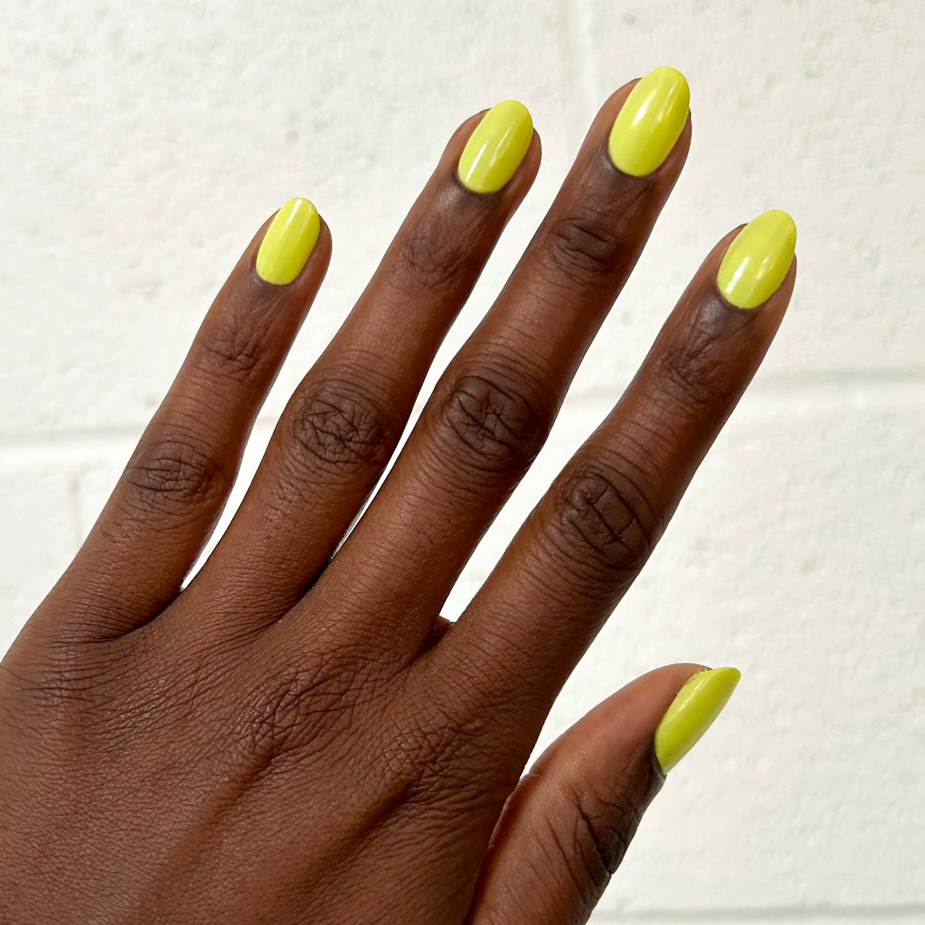Hand with nails painted bright nearly neon yellow Game Set Mani polish for a smooth quick-dry manicure at home