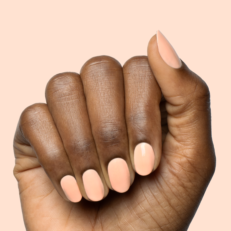 Hand with smooth nails painted in pastel melon shade It’s Serving Melon Cocktails polish for a fresh at-home manicure