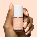 Hand with smooth nails painted in soft pastel melon shade It’s Serving Melon Cocktails nail polish by Olive and June