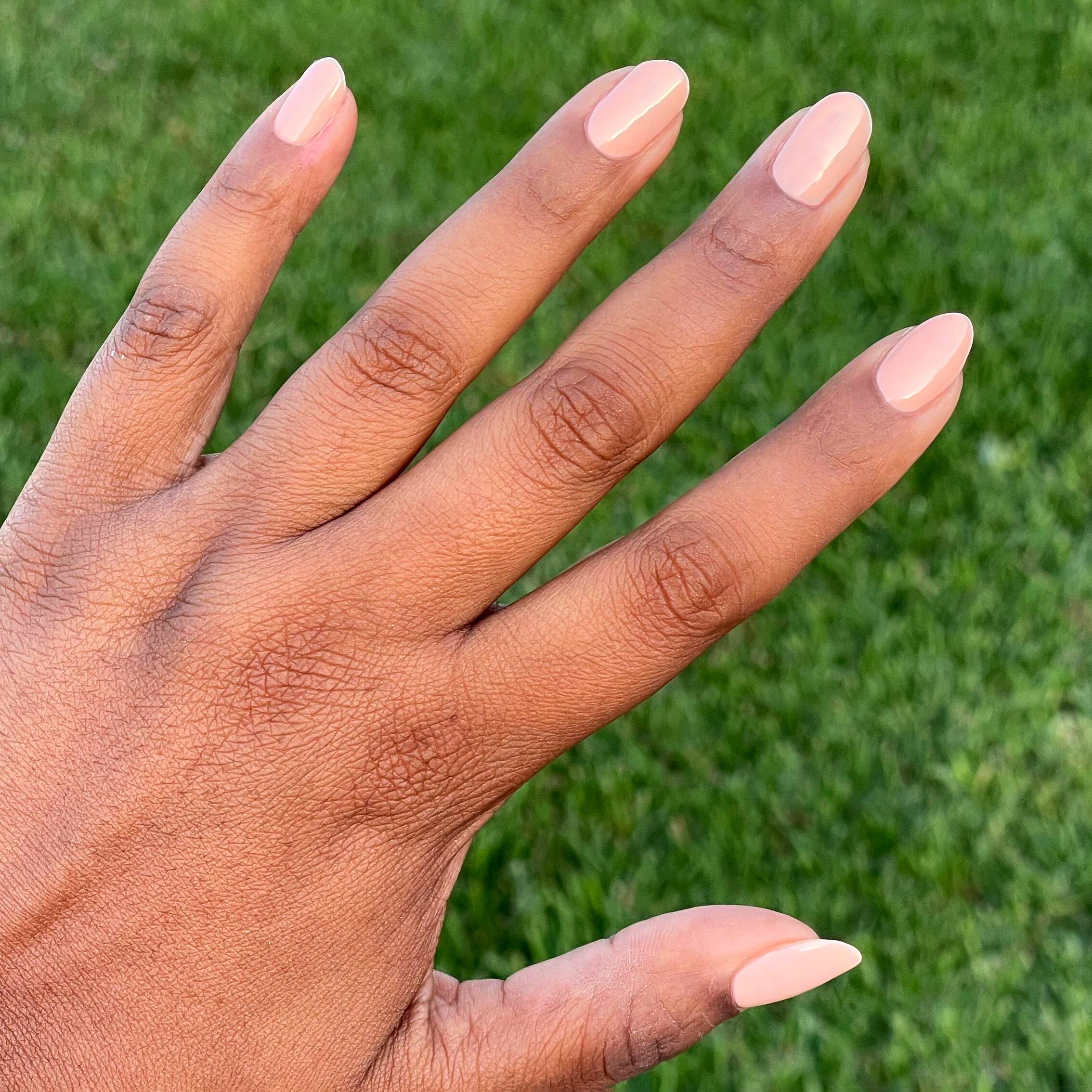 Hand with natural nails coated in pastel melon shade It’s Serving Melon Cocktails for a glossy at-home manicure look