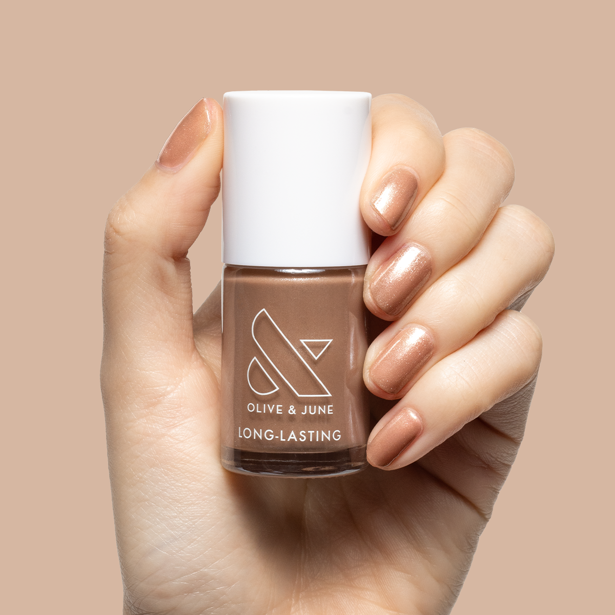 Hand holding Olive and June bottle with nails painted in warm chestnut Coconut Shimmer Gloss polish