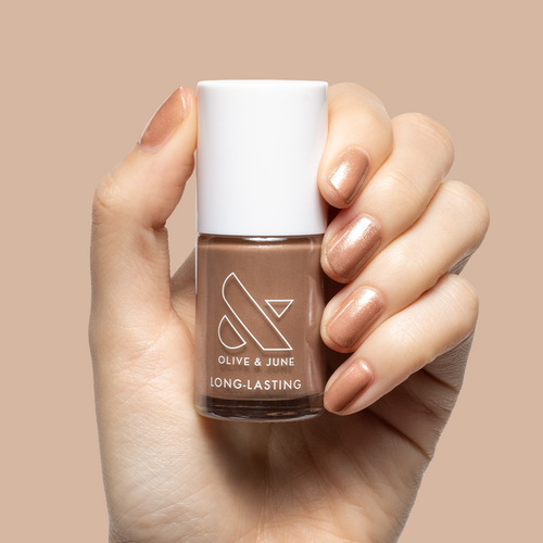 Hand holding Olive and June bottle with nails painted in warm chestnut Coconut Shimmer Gloss polish